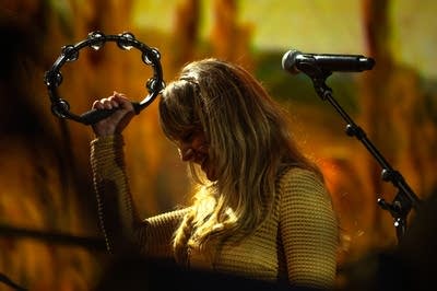 A woman sings and plays tambourine onstage