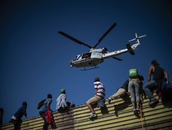 A group of Central American migrants climb the border fence