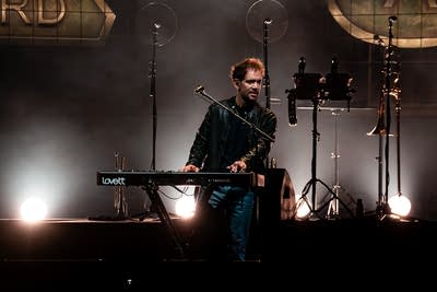 A musician sings and plays keyboards on an outdoor stage