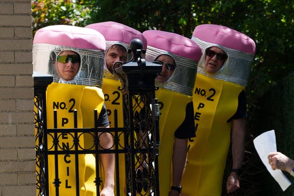 A group of people wait to run out and dance in pencil costumes.
