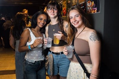 Three friends pose for a photo together inside a music venue