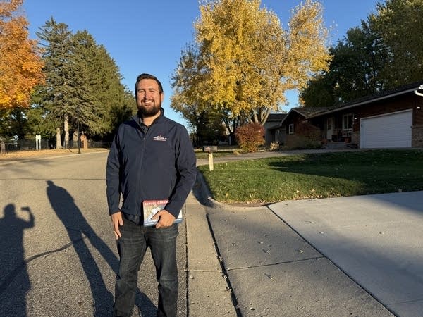 A man stands on a street in a suburb neighborhood.