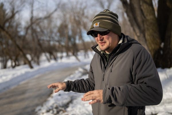 A man stands next to an icy trail