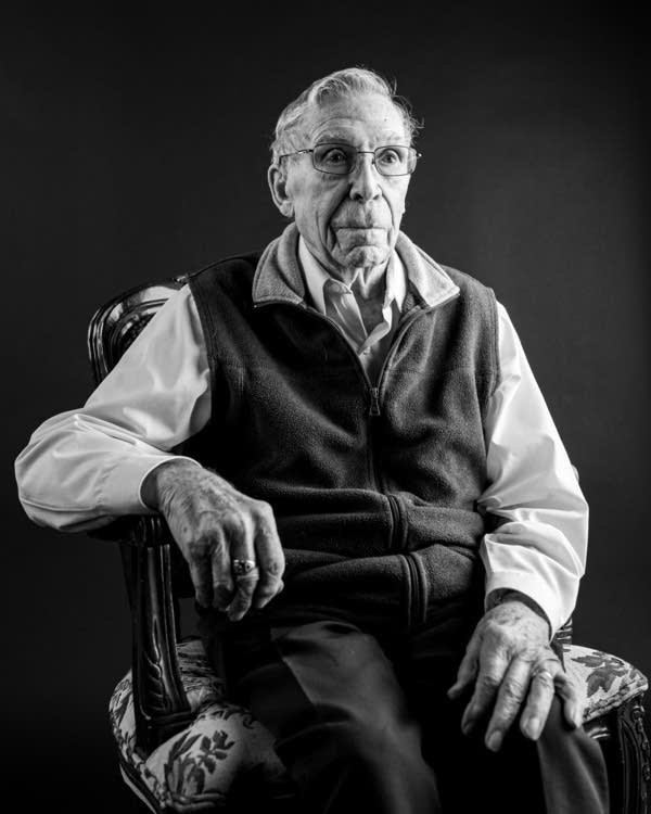 A black and white portrait of a man in a chair.