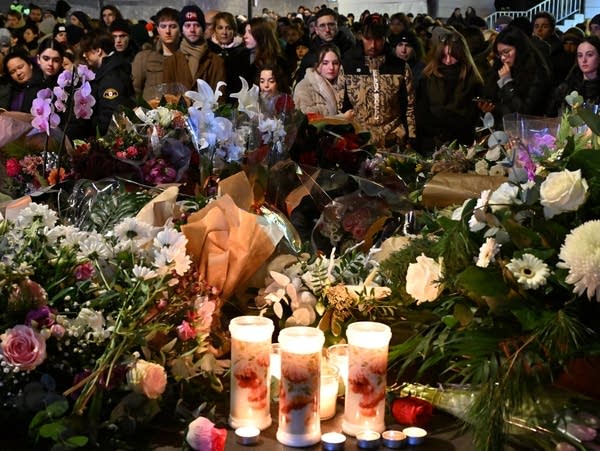 Mourners gather to leave flowers and candles at the scene of a deadly fire