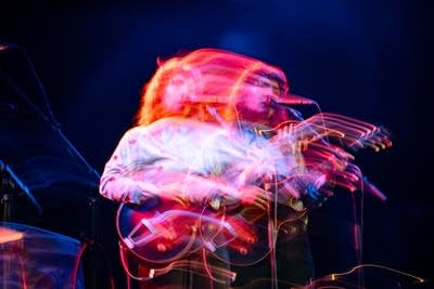 A woman sings and plays guitar onstage in a music venue