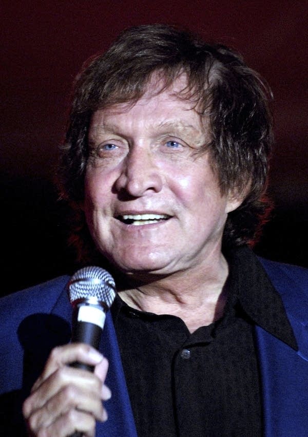 A man sings into a microphone onstage