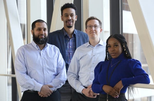 Four people stand near a window.