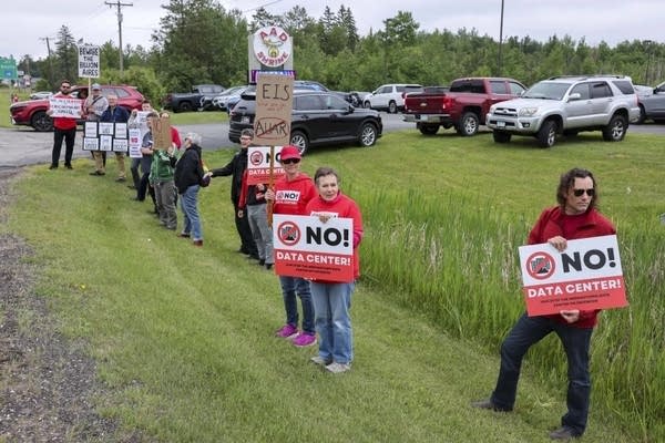 A group holds signs while standing near a highway.