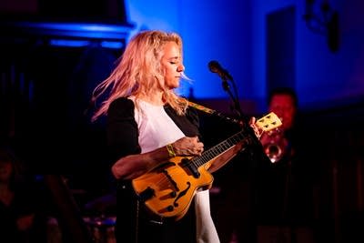 a woman playing an eclectic ukelele on stage