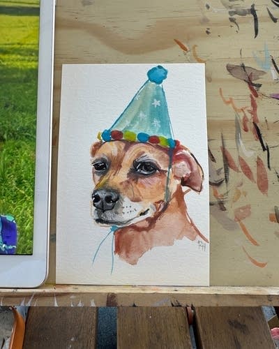 A watercolor portrait of a dog wearing a party hat