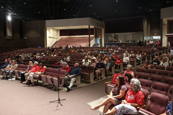 A high school auditorium is roughly half full of event attendees.