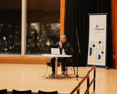 A man speaks to an audience in an auditorium