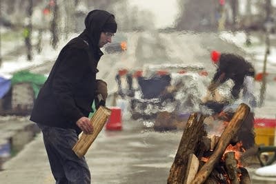 Todd Kimlinger adds wood to a fire.