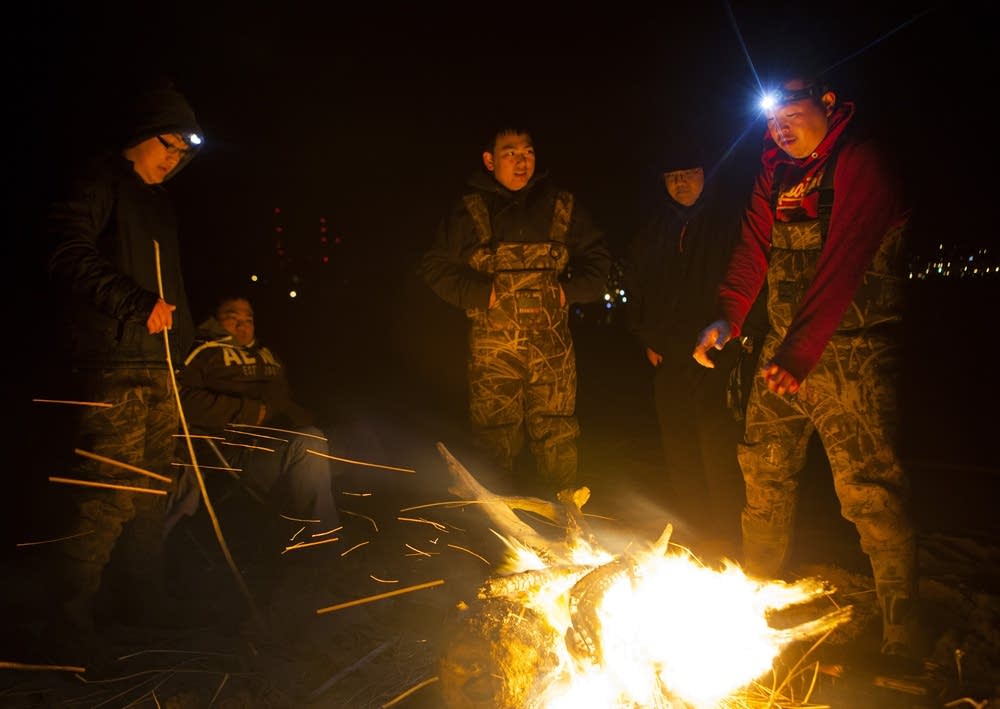 Koua Yang warms himself by a bonfire