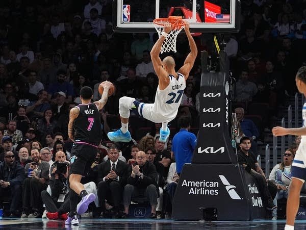 A Timberwolves basketball player swings from the hoop.