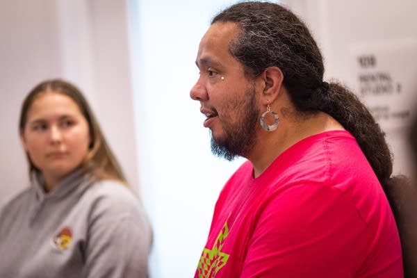 A person wearing a pink t-shirt speaks