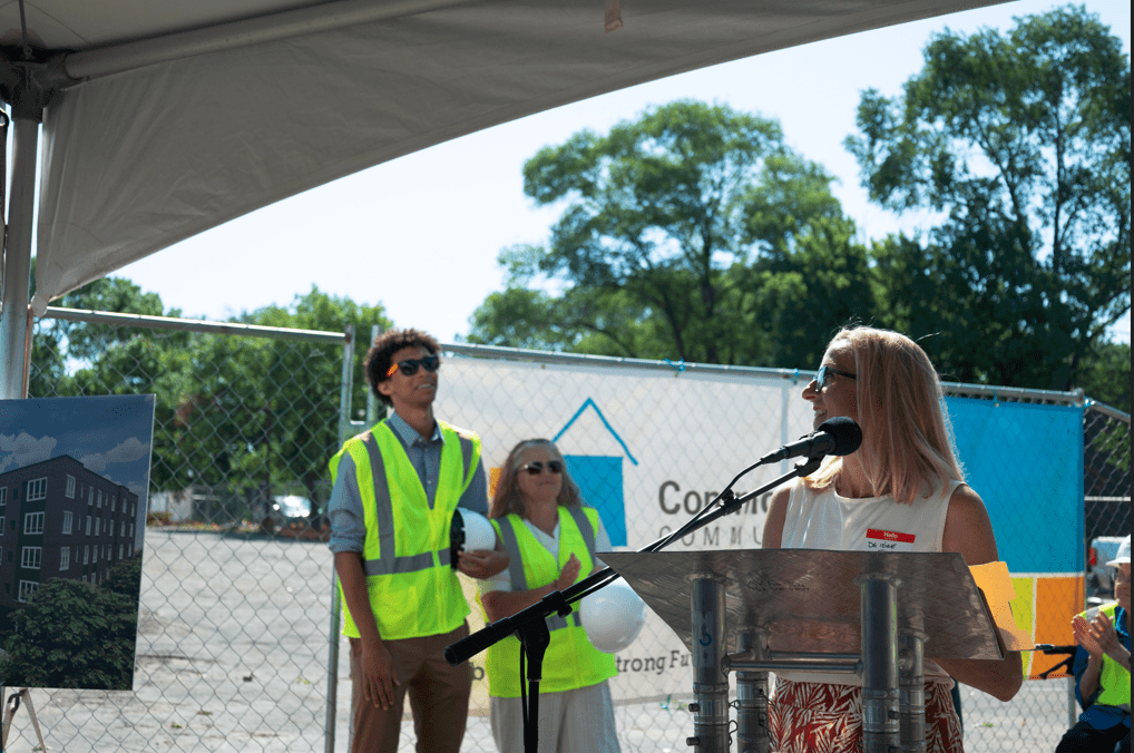 A person stands at a mic and two people watch on