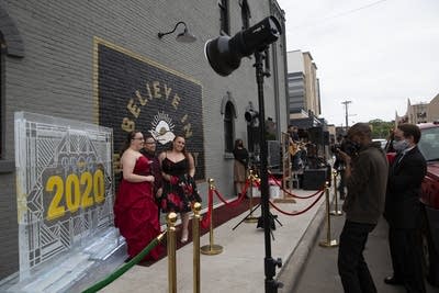 Three teens pose in front of a mural and ice sculpture.