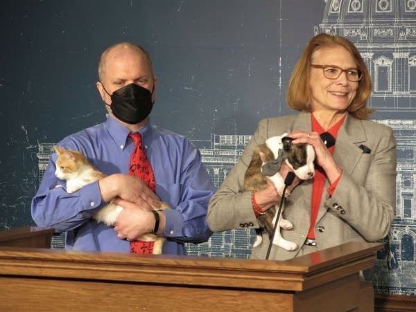 Two people hold pets at a podium