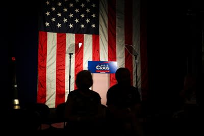 An empty podium in front of an American flag is lit by a spotlight.