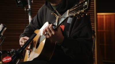 A man sings and plays guitar in a recording studio