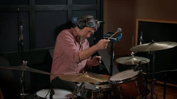 A man plays drums in a recording studio