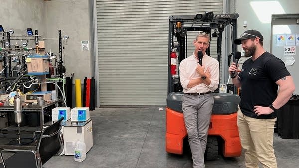 Marketplace host Kai Ryssdal, left, speaks with Nick Steinke of Air Company at its Bushwick plant in Brooklyn, New York. The company makes sustainable aviation fuel for the Department of Defense.