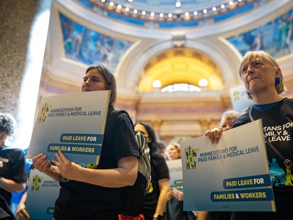 People hold signs in the capitol rotunda