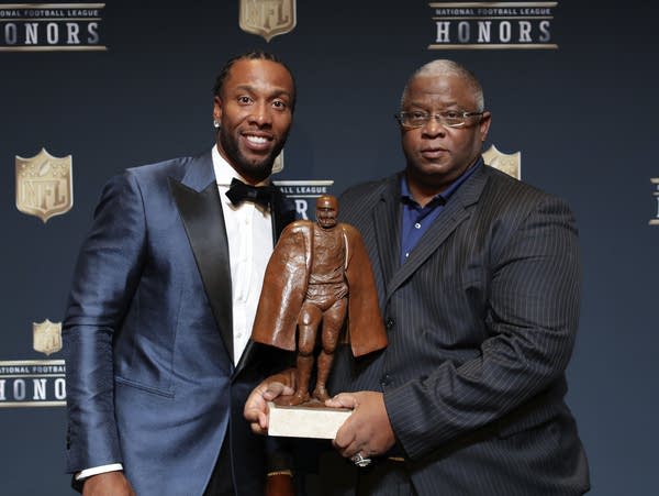 Two men pose with an award