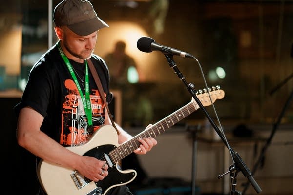 A man plays guitar in a recording studio