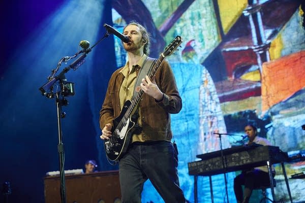 A man sings and plays guitar onstage