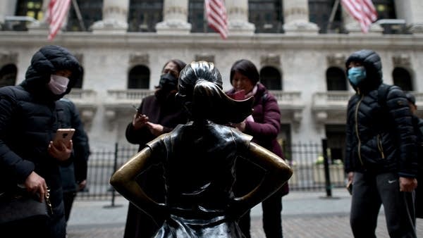 Chinese tourists with facial masks stand in front of the New York Stock Exchange on February 3, 2020 at Wall Street in New York City.