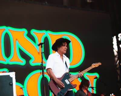 A musician plays guitar on a large outdoor stage