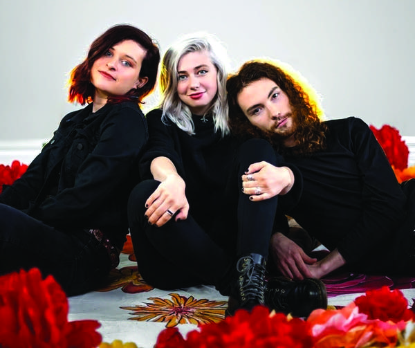 Three people seated among giant flowers