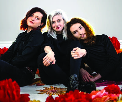 Three people seated among giant flowers