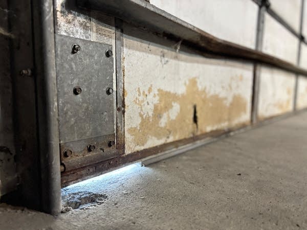 A gap shows light spilling in from a garage door.