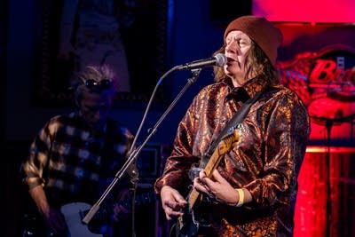 A man sings and plays guitar onstage in a music venue