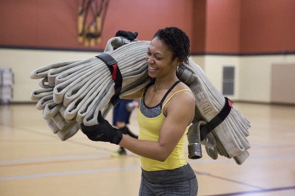 Celeste Sawyers does lunges with a fire hose draped over her shoulder