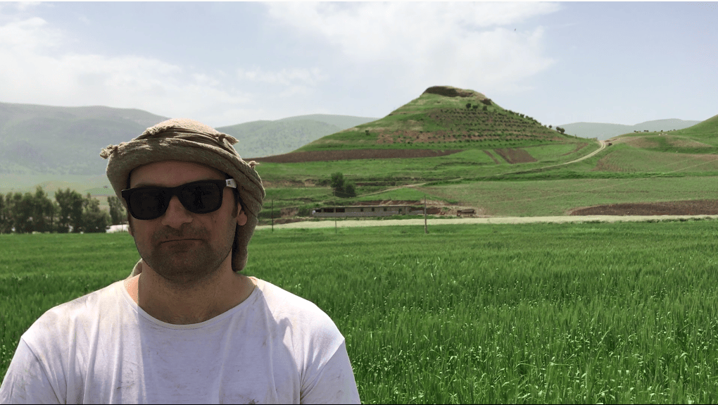 Archaeologist Mark Altaweel stands in front of a mound that appears at the Dinka Settlement Complex excavation site.