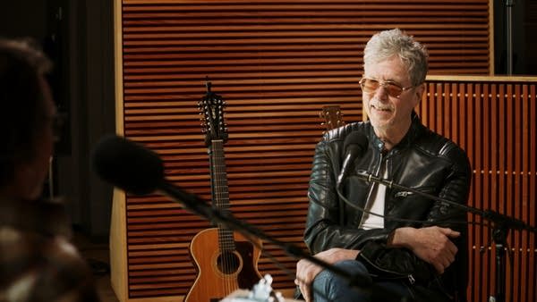 Two men have a conversation in a recording studio