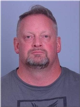man with beard and gray shirt in mugshot