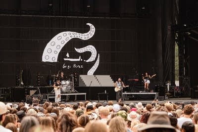 Four musicians performing on a large outdoor stage