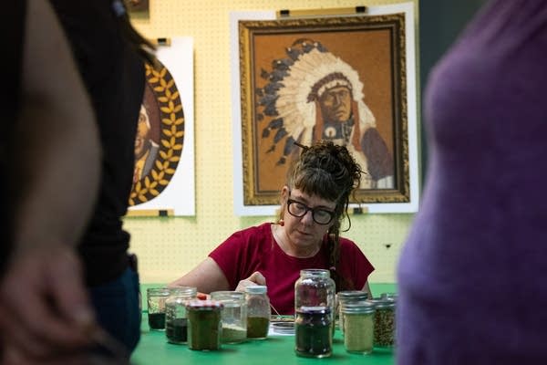 A woman sits at a table and makes art