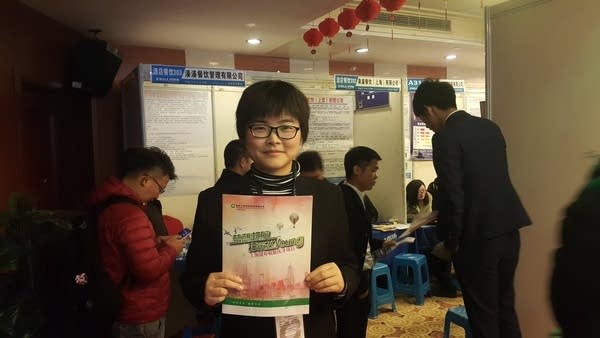 A woman in glasses holds an insurance company brochure.