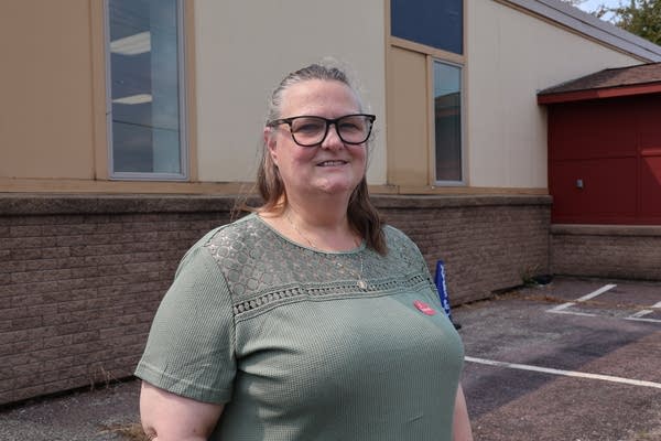 A woman with glasses wearing a green shirt outside