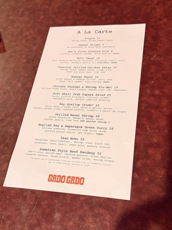 A paper a la carte menu lies on a wood surface