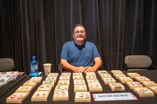 A man sits at a booth with earrings lai
