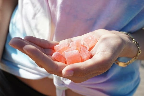 A person holds orange gummie candy