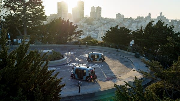 Two self-driving Zoox Robotaxis in a parking lot in San Francisco.